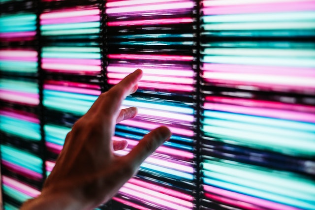 Človek sa dotýka steny, ktorá svieti na ružovo a modro 